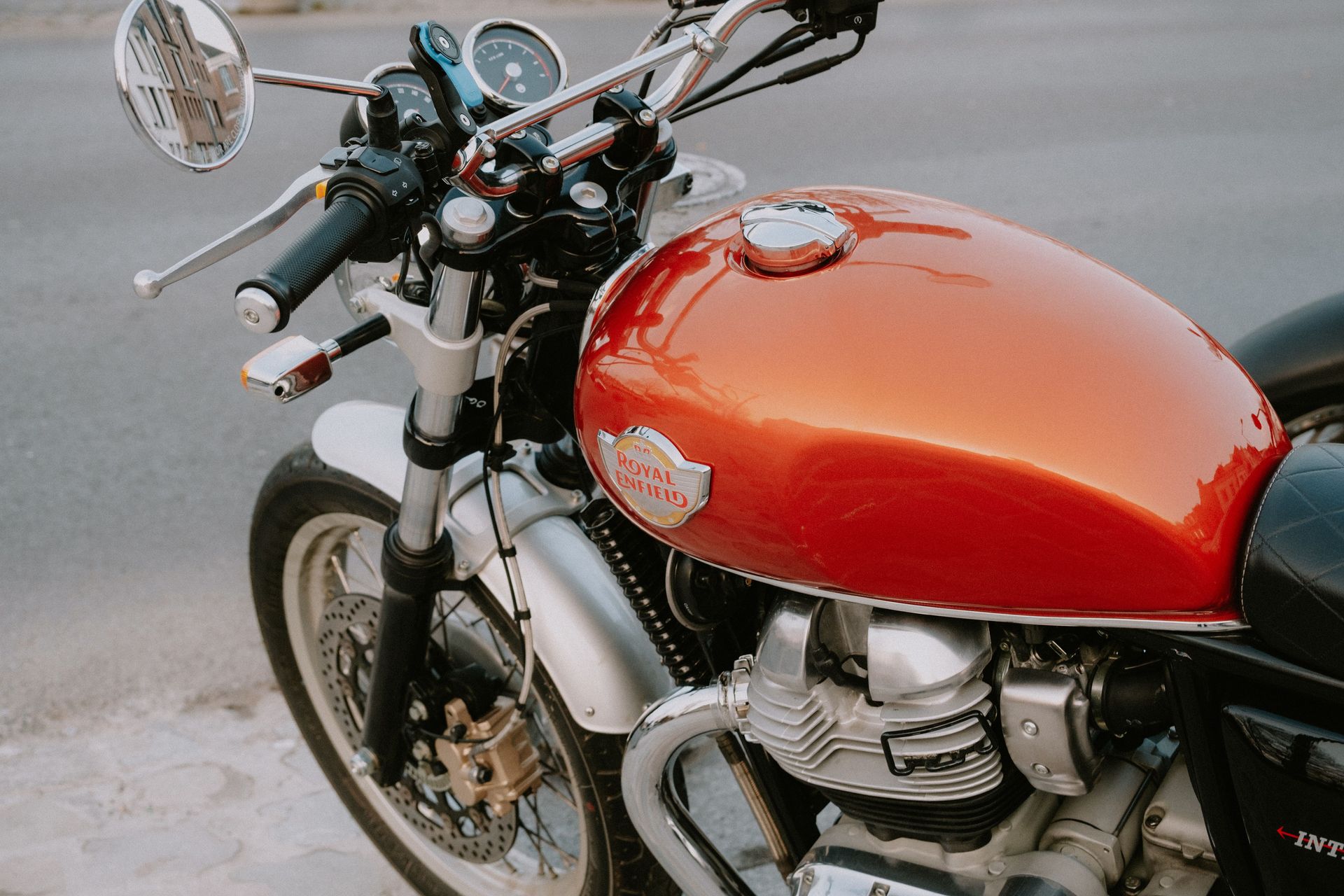 Detailed close-up of a Royal Enfield motorcycle tank with chrome accents on a street.